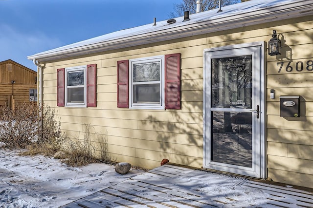 snow covered property entrance featuring a deck