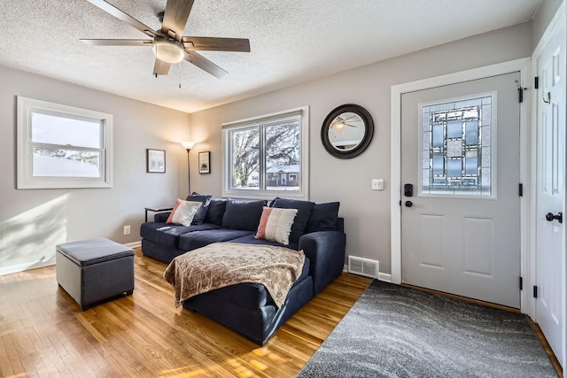 living room featuring ceiling fan, wood-type flooring, and a textured ceiling