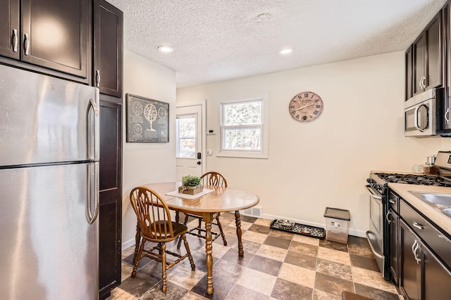 kitchen with dark brown cabinets, a textured ceiling, and appliances with stainless steel finishes