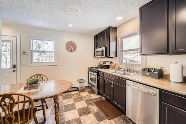 kitchen featuring dark brown cabinetry, sink, stainless steel appliances, and a textured ceiling