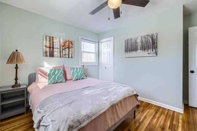 bedroom with dark hardwood / wood-style flooring, ceiling fan, a closet, and a textured ceiling