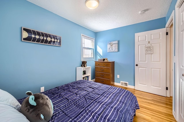 bedroom featuring hardwood / wood-style flooring and a textured ceiling