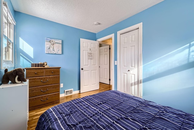 bedroom with hardwood / wood-style flooring, a closet, and a textured ceiling