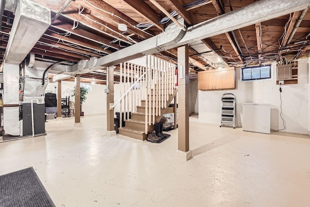 basement featuring fridge, a healthy amount of sunlight, and heating unit