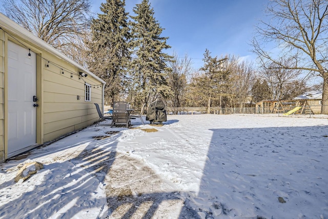 yard layered in snow featuring a playground