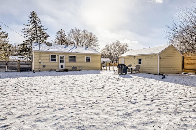 snow covered back of property featuring central AC unit