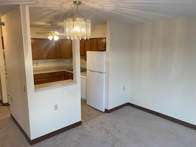 kitchen with pendant lighting, ceiling fan with notable chandelier, light colored carpet, and white fridge