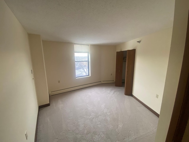 carpeted empty room with a textured ceiling and baseboard heating