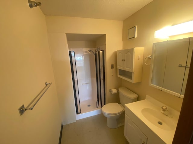 bathroom with vanity, toilet, a textured ceiling, and a tile shower