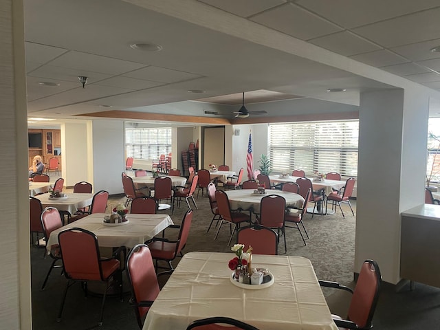 carpeted dining area featuring a paneled ceiling and ceiling fan