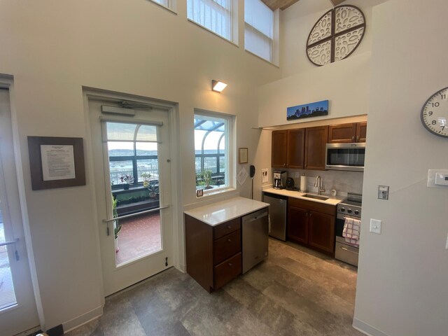 kitchen featuring tasteful backsplash, appliances with stainless steel finishes, sink, and a high ceiling