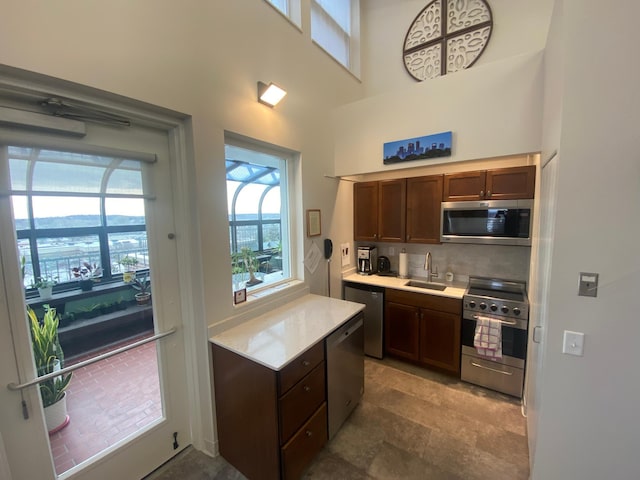 kitchen featuring a high ceiling, appliances with stainless steel finishes, sink, and backsplash