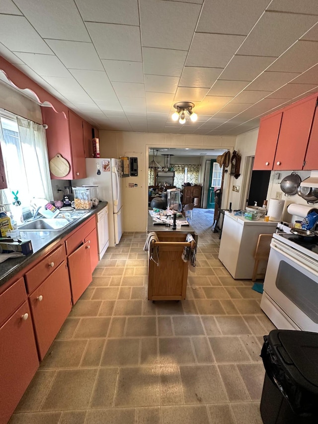 kitchen with white electric range oven, dark countertops, a kitchen island, and a sink