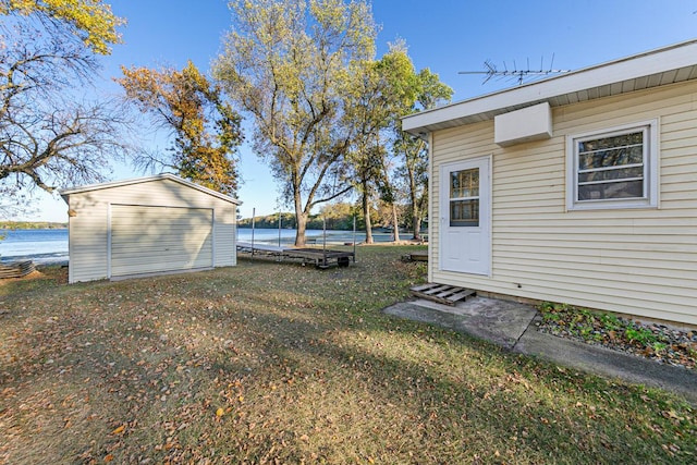 view of yard with a water view, a storage shed, and an outbuilding