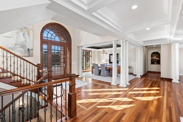 entryway featuring decorative columns, a chandelier, and wood finished floors