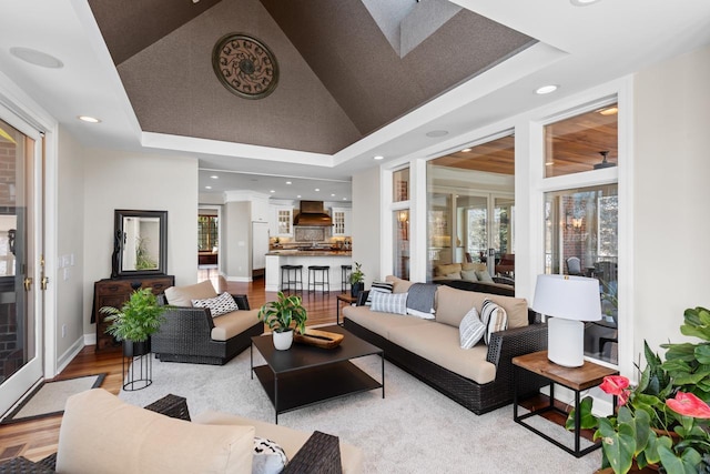 living room with lofted ceiling, a raised ceiling, baseboards, and wood finished floors