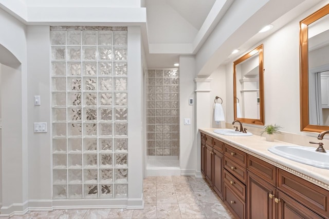 full bathroom with double vanity, walk in shower, a sink, and baseboards