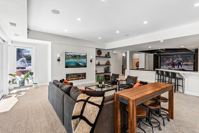 living room with light carpet, recessed lighting, baseboards, and a glass covered fireplace