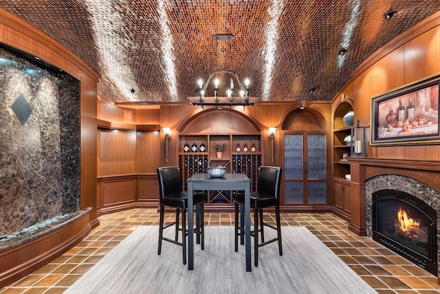 wine room featuring built in shelves, ornamental molding, a high end fireplace, wood walls, and tile patterned flooring