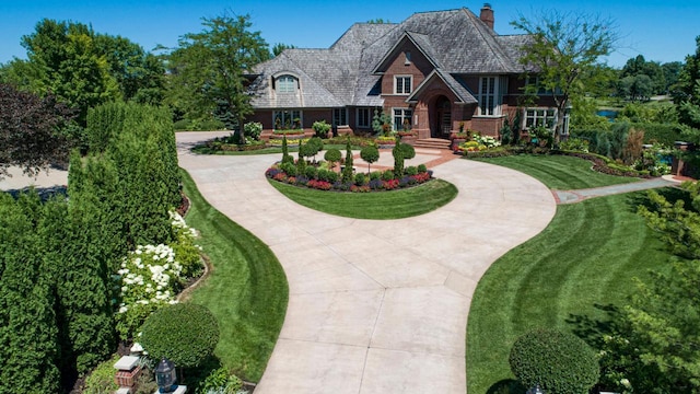 view of front of home with driveway, a chimney, and a front yard