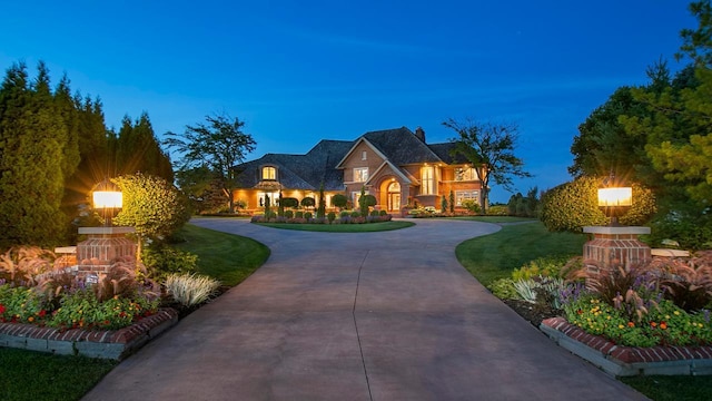 view of front facade featuring stone siding, curved driveway, and a front yard