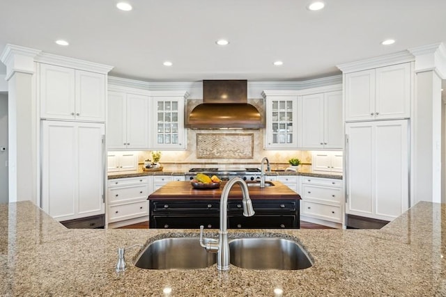 kitchen with premium range hood, a sink, white cabinetry, wooden counters, and backsplash