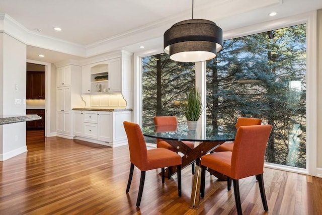 dining space with ornamental molding, wood finished floors, and recessed lighting