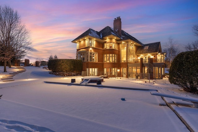 snow covered rear of property with a chimney