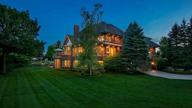 exterior space with concrete driveway, a lawn, and a chimney