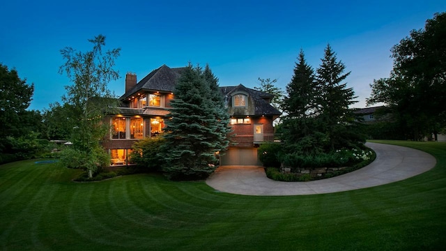 view of front facade with concrete driveway, a front lawn, a chimney, and an attached garage