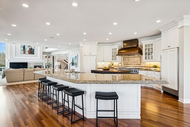 18313 Nicklaus Way, Eden Prairie, MN 55347 - kitchen with a sink, a large island with sink, custom exhaust hood, dark wood-type flooring, and a kitchen bar