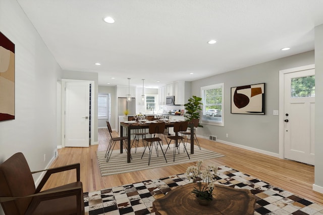 dining room with light wood finished floors, recessed lighting, and baseboards