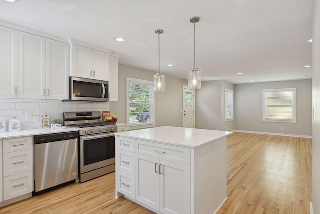 kitchen with pendant lighting, light countertops, decorative backsplash, appliances with stainless steel finishes, and white cabinets