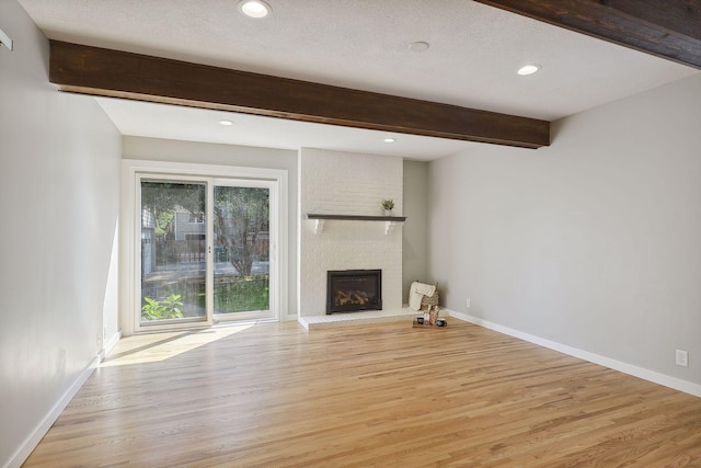 unfurnished living room with beam ceiling, a fireplace, and baseboards