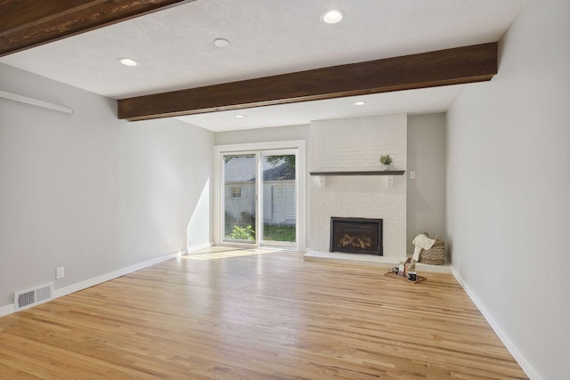 unfurnished living room featuring visible vents, a fireplace, beamed ceiling, and baseboards