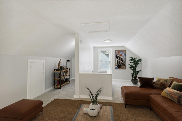 living area with a textured ceiling, light carpet, baseboards, vaulted ceiling, and attic access