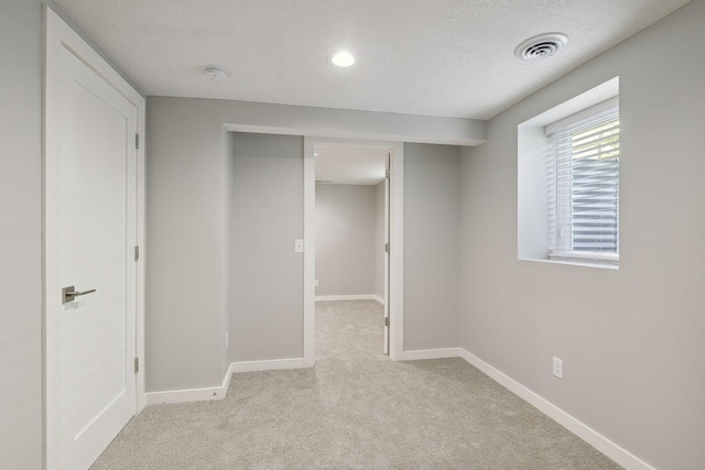 interior space with light carpet, baseboards, visible vents, and a textured ceiling