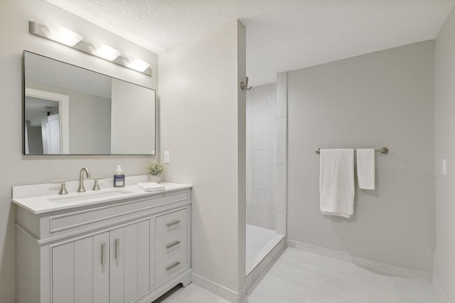 bathroom featuring baseboards, a tile shower, a textured ceiling, and vanity