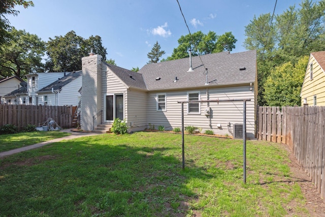 back of house with entry steps, a lawn, a fenced backyard, and central air condition unit