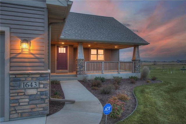 exterior entry at dusk featuring a yard and covered porch