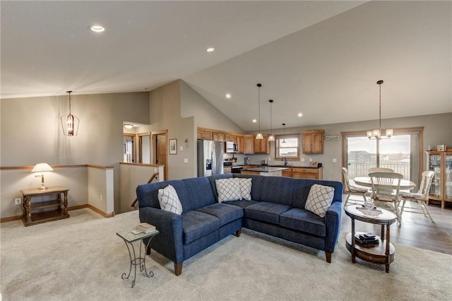 carpeted living room featuring high vaulted ceiling, a chandelier, and sink