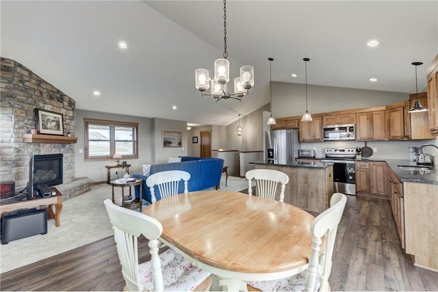 dining area featuring a stone fireplace, dark hardwood / wood-style floors, high vaulted ceiling, sink, and a chandelier