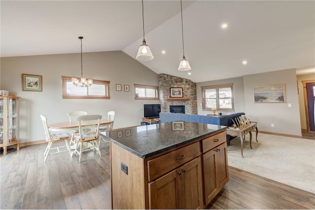 kitchen featuring pendant lighting, a fireplace, lofted ceiling, dark stone counters, and a center island