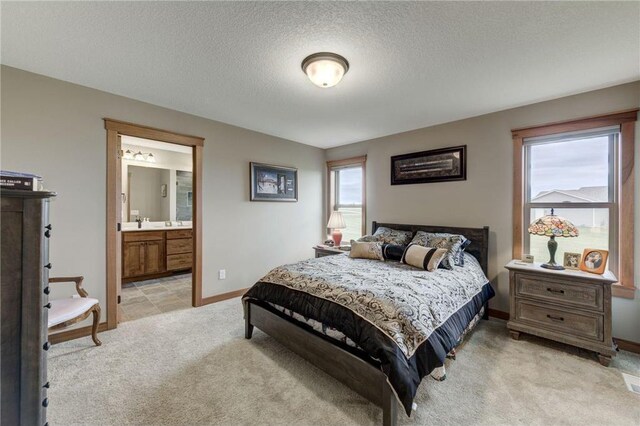 carpeted bedroom featuring ensuite bathroom and a textured ceiling