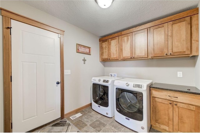 washroom with washer and dryer, cabinets, and a textured ceiling