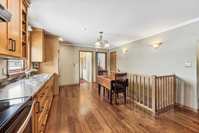 kitchen with sink, dark stone counters, ornamental molding, dark wood-type flooring, and an inviting chandelier