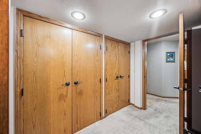 hall featuring light carpet and a textured ceiling