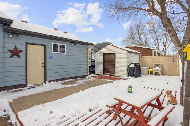 snow covered patio featuring a grill and a shed