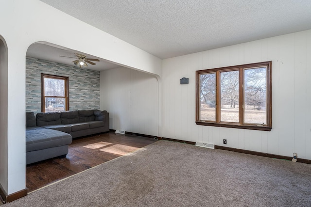 living room featuring ceiling fan, dark wood-type flooring, and a textured ceiling