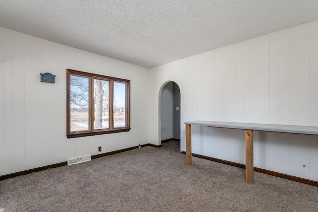 unfurnished room with a textured ceiling and carpet flooring